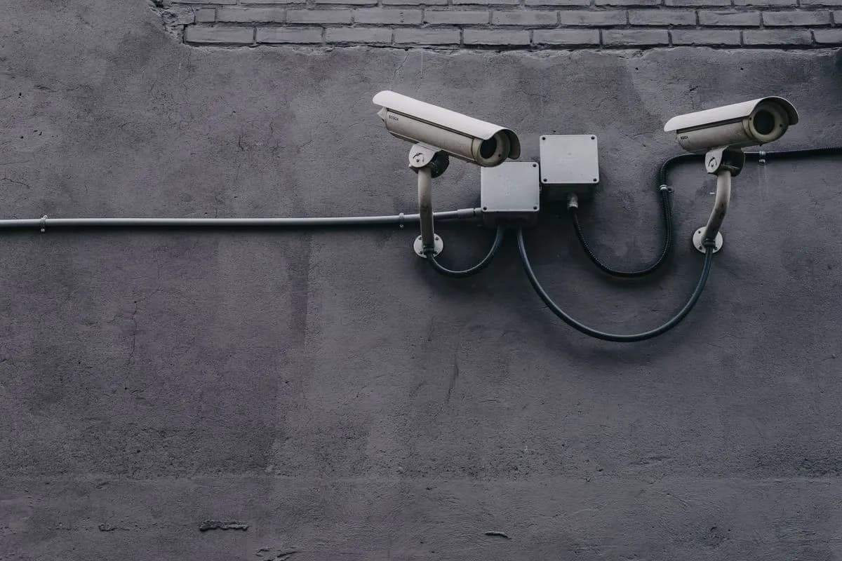 Two bullet cameras on a dark wall facing opposite directions